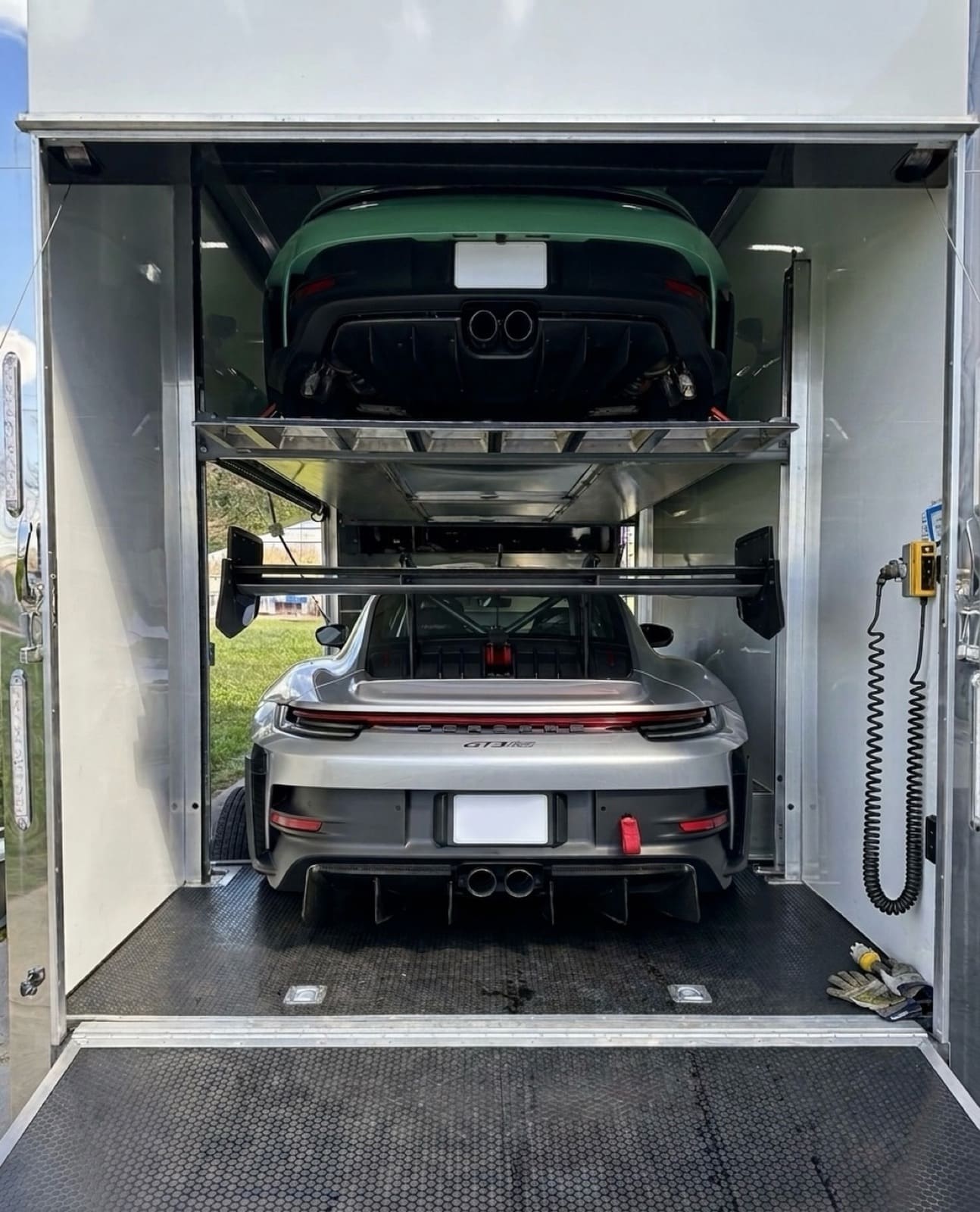 Porsche 911 GT3 RS and a second Porsche double-decked inside an enclosed trailer